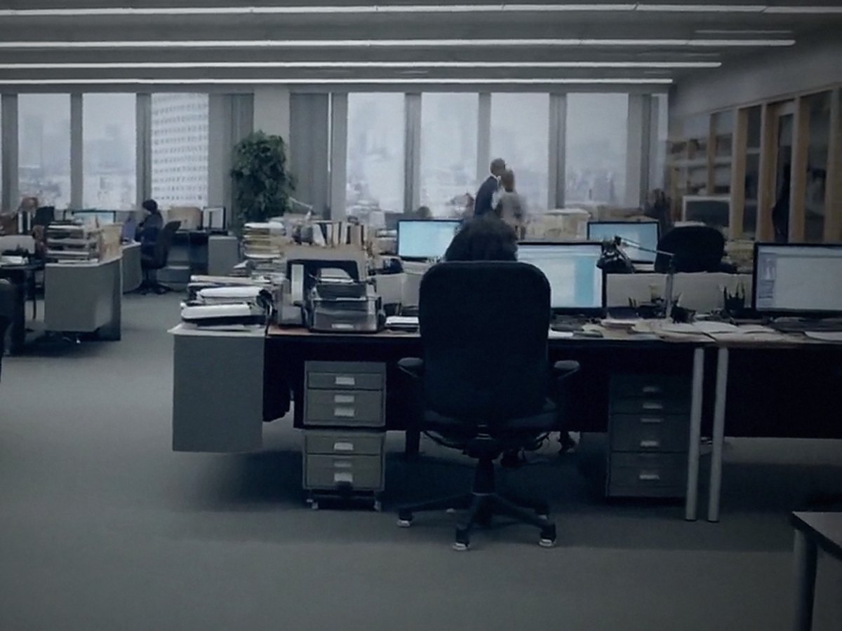 An open, orderly office floor with clear desks and a team working independently